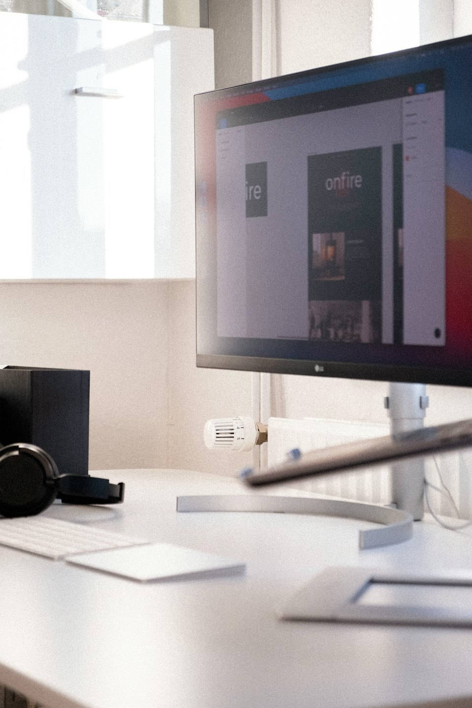 Modern desk with computer displaying website design and headphones.